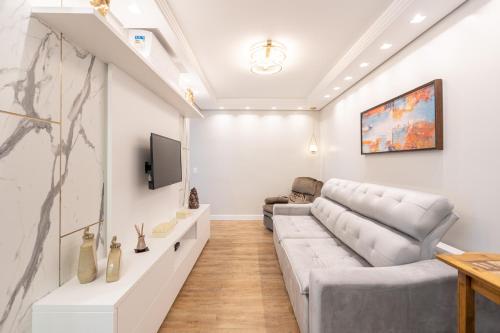 a living room with a couch and a tv at Apto a 150m DA PRAIA e 15min BETO CARREIRO com WI-FI, PISCINA, PORTARIA 24h, PLAYGROUND INFANTIL, QUADRA DE ESPORTES sacada com CHURRASQUEIRA e vaga de GARAGEM in Piçarras