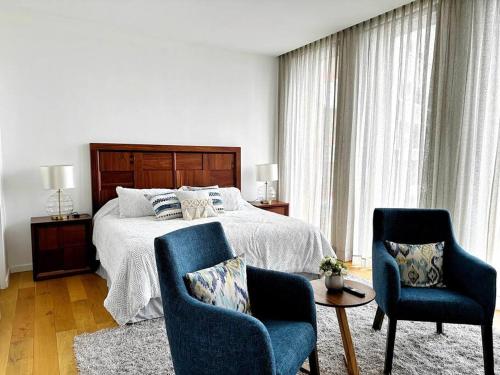 sypialnia z łóżkiem i 2 niebieskimi krzesłami w obiekcie Homely Escape in Providencia. w mieście Guadalajara
