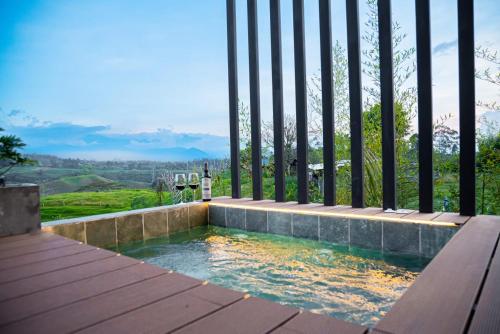 a swimming pool with a fence and a bottle of wine at Ecohotel Monte Tierra Habitaciones y Glamping in Filandia