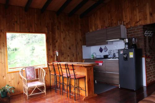a kitchen with a counter and a refrigerator and a table at cabañas Arcoíris del lago Nº 2 in Pasto