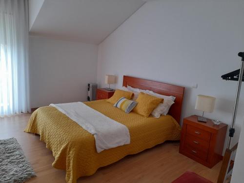 a bedroom with a bed with a yellow blanket and pillows at Azoresaccommodation in Lagoa