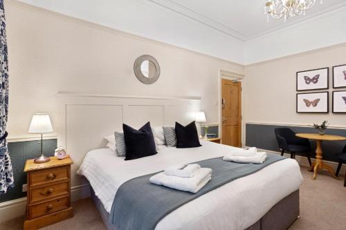 Fountains Guest House - Harrogate Stays في هاروغايت: غرفة نوم بسرير كبير عليها منشفتين