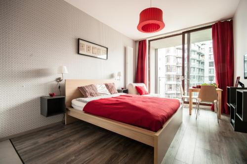 ワルシャワにあるApart Studio Warszawaのベッドルーム1室(赤いシーツ付きのベッド1台、窓付)