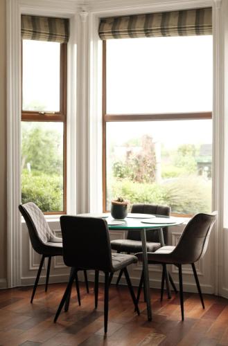 a table and chairs in a room with windows at Antrim Road Apartments Belfast in Belfast