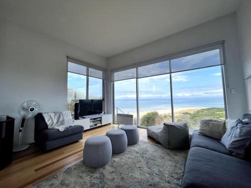 a living room with a couch and a large window at Three Little Birds at Freycinet in Coles Bay