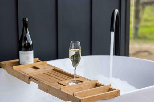a wine glass in a wooden tray with a bottle of wine at Mt Duneed Estate in Mount Duneed