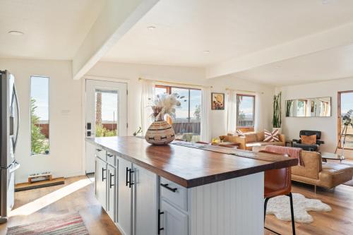 a kitchen with a large island in a living room at Mojave Lofi - Bright and Airy home 25 min from Joshua Tree National Park - Hot Tub, Cal-King Beds, Game Room in Yucca Valley
