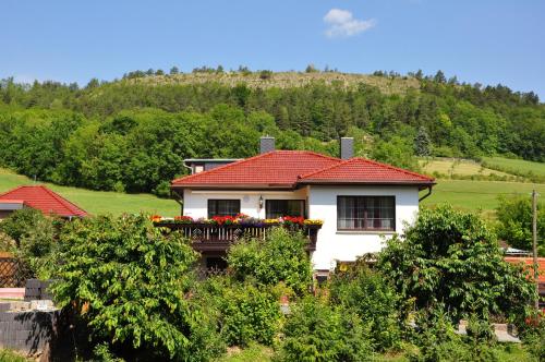 a white house with a red roof with a balcony at Hotel Haus Orchideental Jena in Jena
