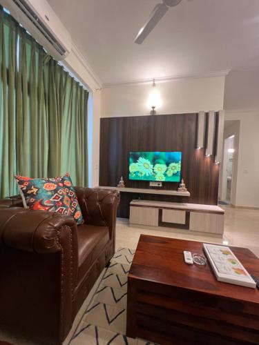 a living room with a brown couch and a tv at Panorama Haven With Swimming Pool in Lucknow