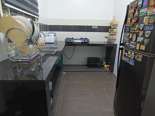 a kitchen with a sink and a refrigerator with magnets at Afya Alya Guesthouse Melaka in Melaka