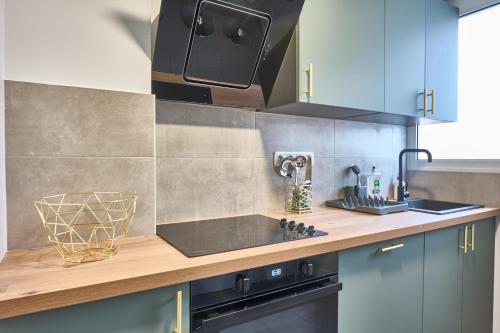 une cuisine avec un évier et une cuisinière dans l'établissement Éclat Doré Bondy Suites Free Parking, à Bondy