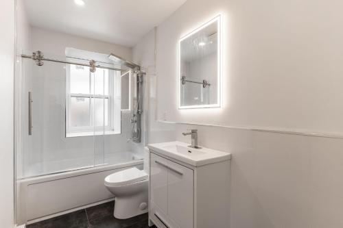 a white bathroom with a toilet and a sink at Spacious 2 bedroom apartment - 02 in Montreal
