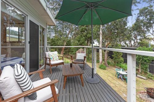 a patio with a green umbrella on a deck at Barca View Cottage in Apollo Bay