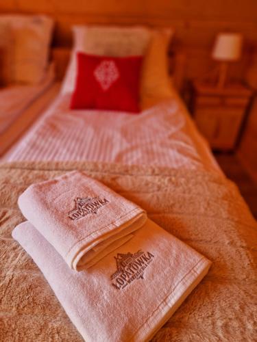 a bed with two towels on top of it at Góralski Domek Łopatówka z kominkiem i Banią - Jacuzzi! in Murzasichle