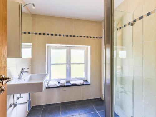 ein Bad mit einem Waschbecken und einem Fenster in der Unterkunft Numéro Trois in Aywaille