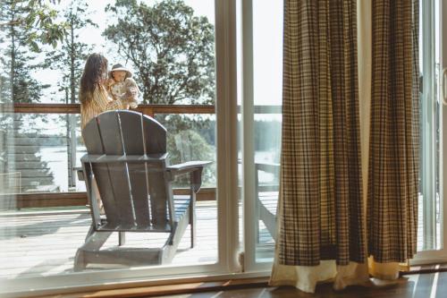 a woman holding a child standing on a porch looking out the window at Page's Inn on Silva Bay in Gabriola