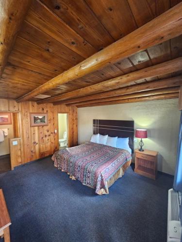 Redrock Country Inn في كاناب: غرفة نوم بسرير وسقف خشبي