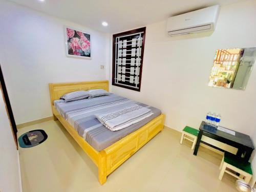 ein Schlafzimmer mit einem Bett und einem Tisch und einem Fenster in der Unterkunft KENPI Homestay in Hue