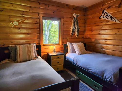 two beds in a log cabin with a window at Belleayre Lodge in Pine Hill
