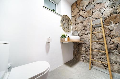 baño con pared de piedra y aseo en Villa Cacemar Salobre, en Las Palmas de Gran Canaria