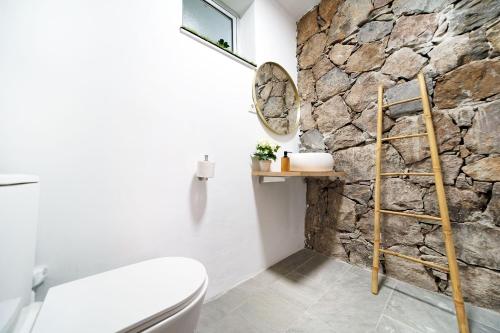 a bathroom with a stone wall and a toilet at Villa Cacemar Salobre Golf in Las Palmas de Gran Canaria