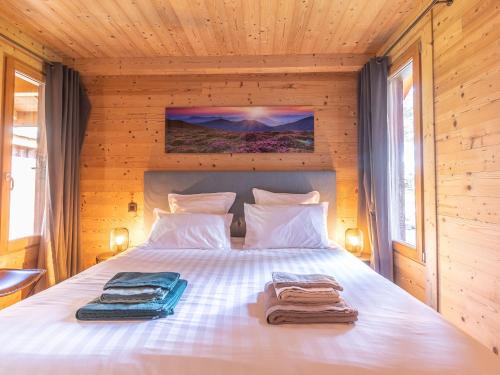 ein Schlafzimmer mit einem Bett mit zwei Handtüchern darauf in der Unterkunft Luxe et détente : Lodge avec SPA privatif et accès piscine, golf, et aire de jeux. - FR-1-582-39 in Le Chambon-sur-Lignon