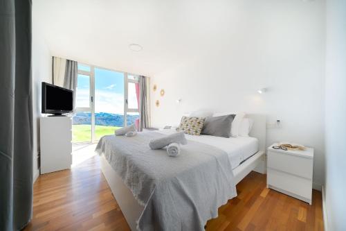 Habitación blanca con cama y TV en Villa Cacemar Salobre, en Las Palmas de Gran Canaria