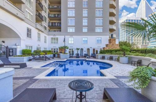 an apartment patio with a pool and tables and chairs at Spacious 2 Bed, 2 Bath Uptown Gem in the Heart of the City-Parking-Wi-Fi-Balcony-Walk to BOA Stadium in Charlotte