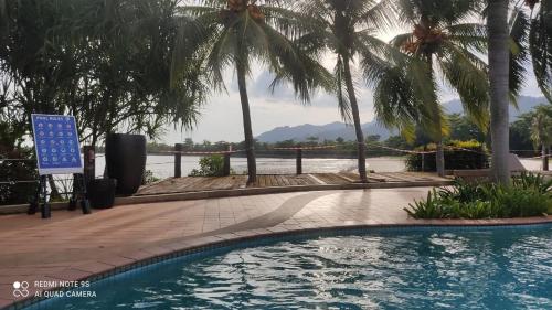 a swimming pool at a resort with palm trees at Villa Dalam laut 530 in Pantai Cenang