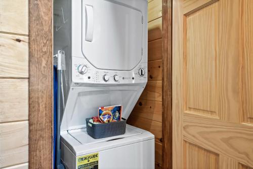a washer and dryer sitting on top of a refrigerator at SmokiesBoutiqueCabins would love to host you at Dolly's Cute Cabin! 4 Suites with Private Bathrooms - Hot Tub, Fire Pit, Game Room, Resort Pool open Memorial Day through Labor Day! in Gatlinburg