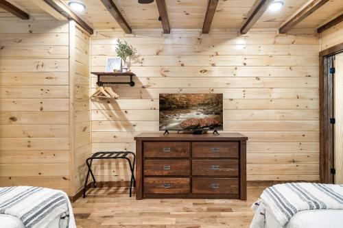 a bedroom with wooden walls and a wooden dresser at SmokiesBoutiqueCabins would love to host you at Dolly's Cute Cabin! 4 Suites with Private Bathrooms - Hot Tub, Fire Pit, Game Room, Resort Pool open Memorial Day through Labor Day! in Gatlinburg