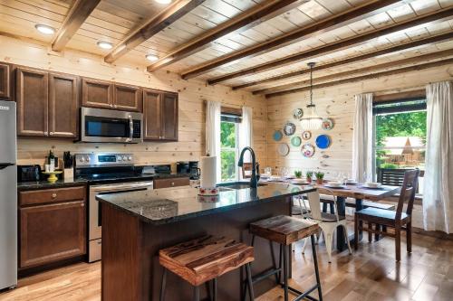a kitchen with wooden cabinets and a table with chairs at SmokiesBoutiqueCabins would love to host you at Dolly's Cute Cabin! 4 Suites with Private Bathrooms - Hot Tub, Fire Pit, Game Room, Resort Pool open Memorial Day through Labor Day! in Gatlinburg