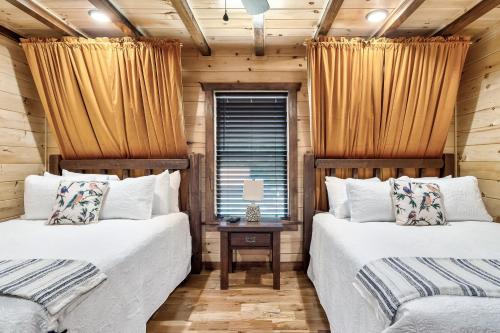 a bedroom with two beds and a table with a window at SmokiesBoutiqueCabins would love to host you at Dolly's Cute Cabin! 4 Suites with Private Bathrooms - Hot Tub, Fire Pit, Game Room, Resort Pool open Memorial Day through Labor Day! in Gatlinburg