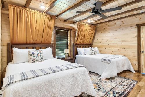 SmokiesBoutiqueCabins would love to host you at Dolly's Cute Cabin! 4 Suites with Private Bathrooms - Hot Tub, Fire Pit, Game Room, Resort Pool open Memorial Day through Labor Day! في غاتلينبرغ: غرفة نوم بسريرين ومروحة سقف