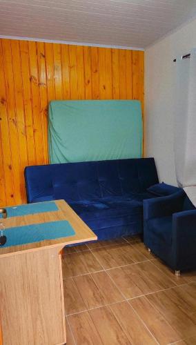 een blauwe bank in een kamer met een houten muur bij Studio Marangoni Hospedagem in Treze Tílias