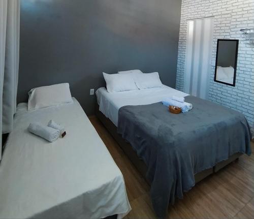 two beds in a hotel room with white sheets at Quarto privativo no centro 01 in Itapira