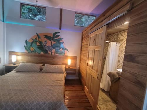 1 dormitorio con 1 cama y pared de madera en Ponci’s Gate to Gaia Holistic Center, en Bocas Town