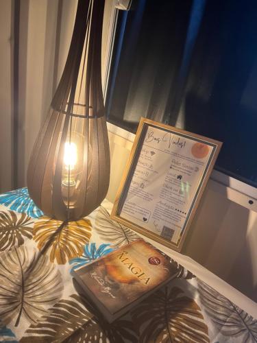 a lamp and a book and a sign on a bed at Recanto Monte Trigo casa Container in São Francisco do Sul