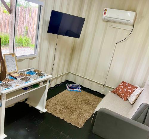 a room with a desk and a tv and a couch at Cabana Monte Trigo in São Francisco do Sul