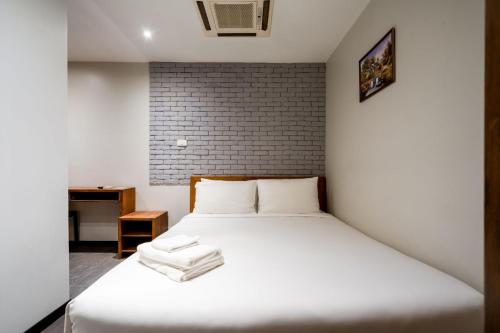 GO INN Sukhumvit-Bts Asoke-Phrom Phong โกอินน์ สุขุมวิท في Bang Kapi: سرير أبيض في غرفة بجدار من الطوب