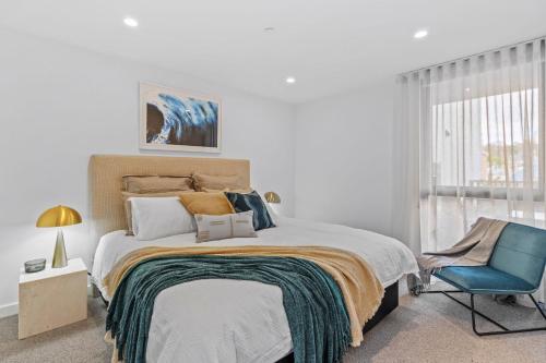 1 dormitorio con 1 cama y 1 silla azul en Designer Apartment - giant terrace - city location, en Hobart