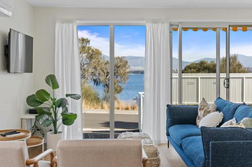 a living room with a blue couch and a view of the ocean at Rose Bay Riverfront - Dreamy Luxury by the Water in Montagu Bay