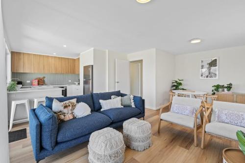a living room with a blue couch and a kitchen at Rose Bay Riverfront - Dreamy Luxury by the Water in Montagu Bay