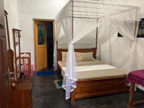 a bedroom with a wooden bed with a canopy at Sayura Beach Hotel in Mirissa