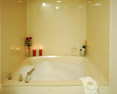 a bathroom with a bath tub with two candles at Zainee Inc Budgetel Inn and Suites in Augusta