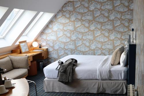 une chambre avec un lit, un bureau et un canapé dans l'établissement Le Pergolèse Paris Champs Elysées, à Paris