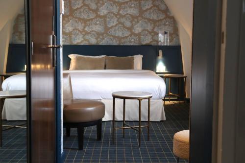 a bedroom with a bed and a chair and a table at Le Pergolèse Paris Champs Elysées in Paris