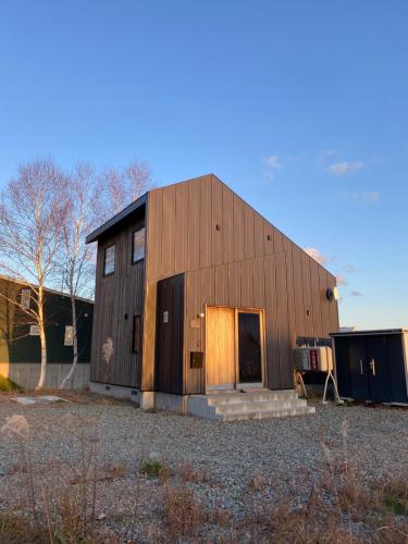a large wooden barn with a door in a yard at Momo Niseko in Niseko