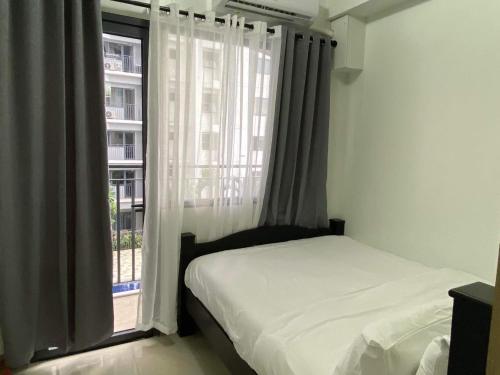 a bedroom with a bed and a window at SHORE RESIDENCE D18 shortwalk Mall of asia near airport in Manila
