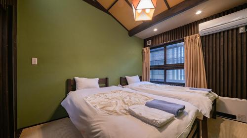 a green room with two beds and a window at WAT RESORT 飛騨まちやど 藤 in Takayama
